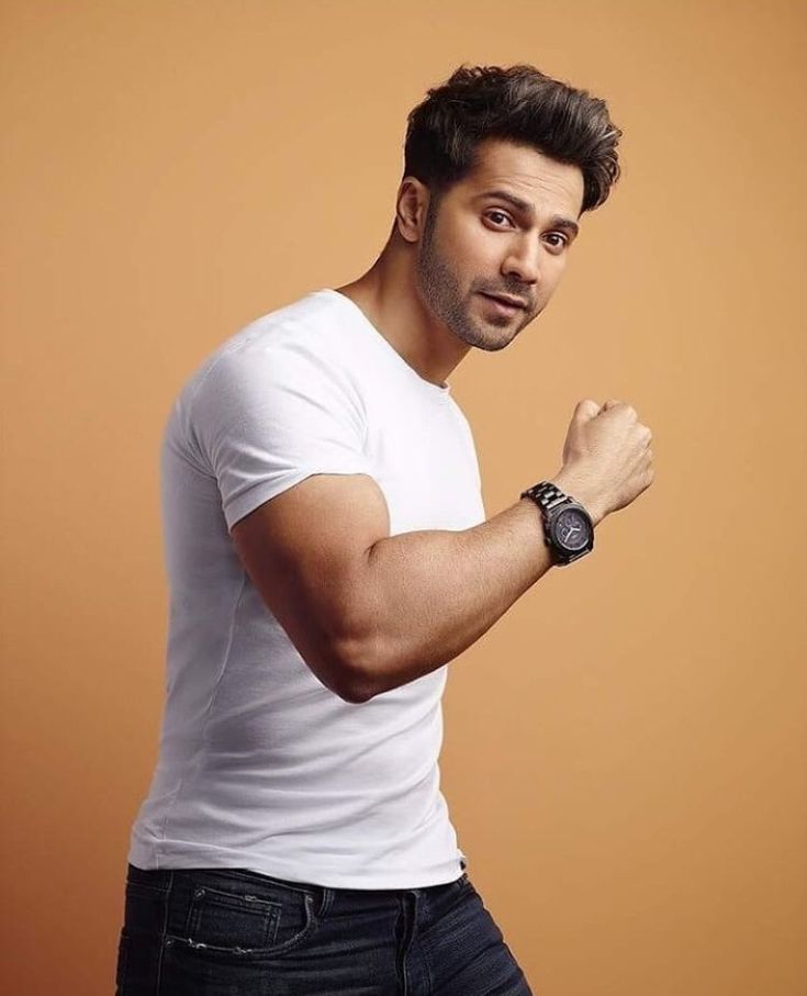 a man with a watch on his wrist posing for a photo in front of an orange background