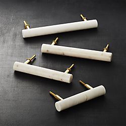 four white marble and gold - plated brass drawer pulls on a black table top