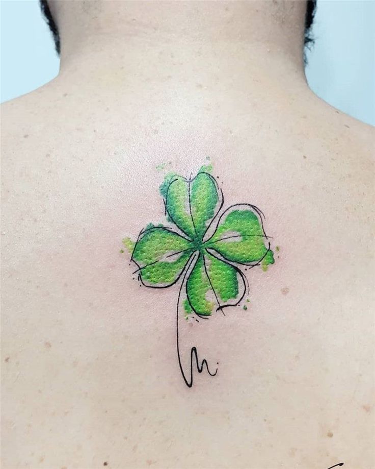 a green clover tattoo on the back of a woman's upper body, with watercolor