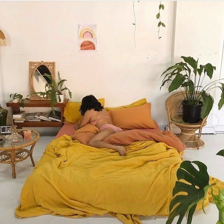 a woman laying on a bed in a room with plants and potted plants behind her