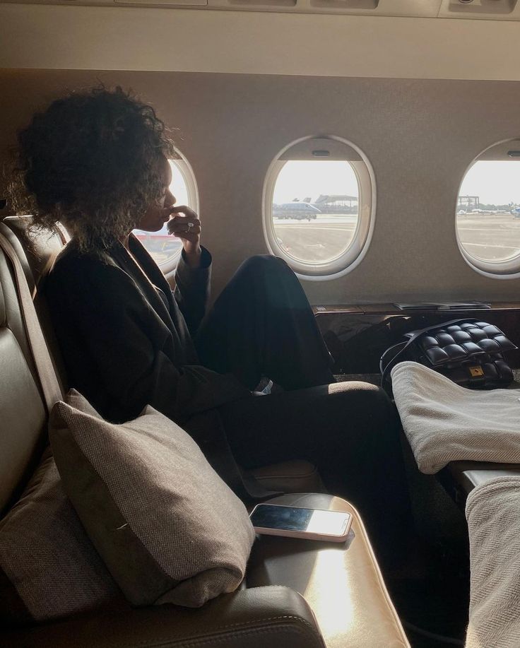 a woman sitting on an airplane seat looking out the window at the planes tarmac