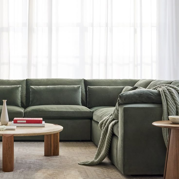 a living room with a large sectional couch and coffee table in front of the window