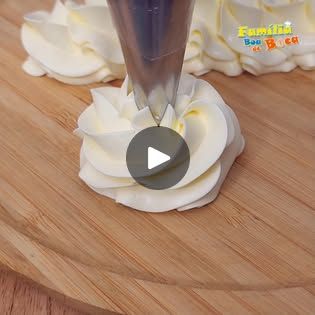 a cake with white frosting being cut on a wooden table and surrounded by icing