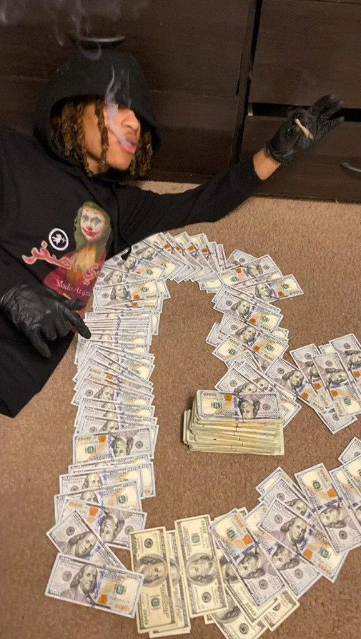 a person sitting on the floor with money in front of her and making a heart shape