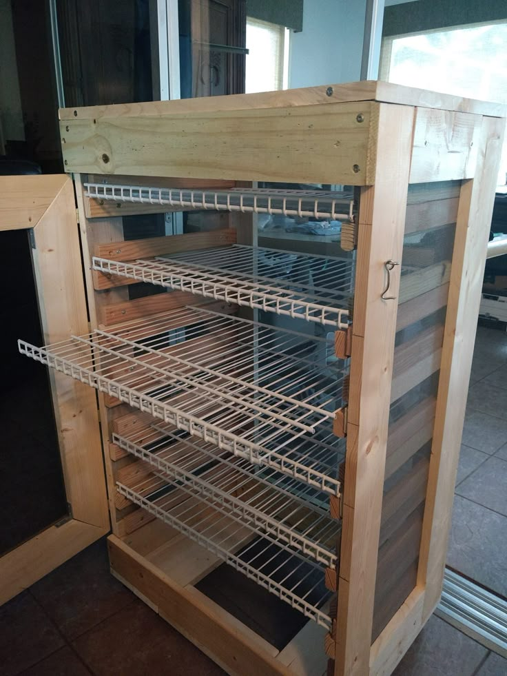 an empty wooden cabinet with shelves and wire on the bottom, in front of a sliding glass door