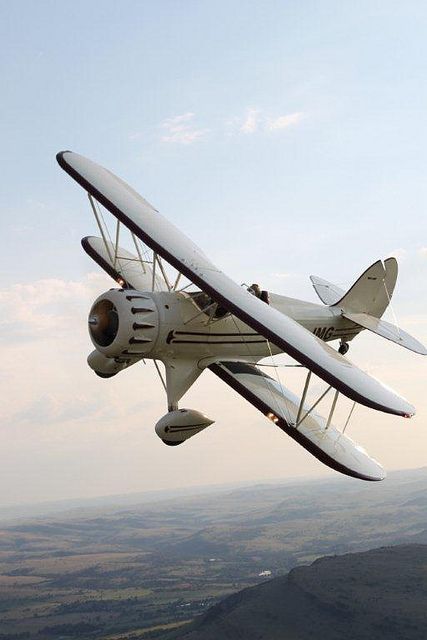 an airplane flying in the air with mountains in the background