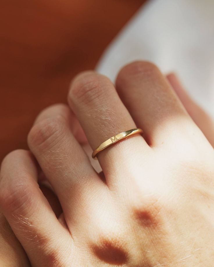 a close up of a person's hand with a gold ring on their finger