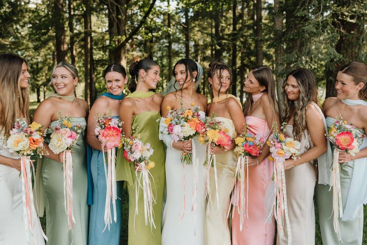 a group of women standing next to each other wearing dresses and holding bouquets in their hands