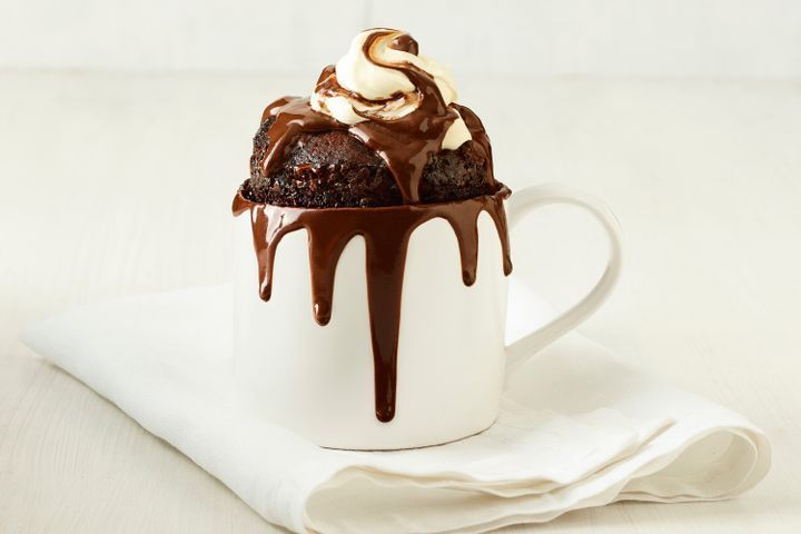 a chocolate cupcake with whipped cream and chocolate drizzled on the top