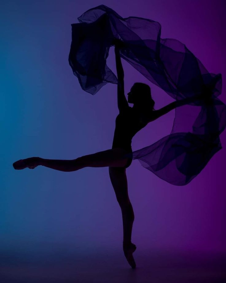 a woman is dancing in the dark with her arms up and one leg behind her head