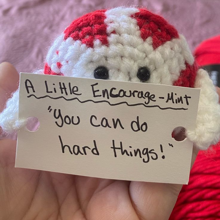 a small red and white crocheted ball of yarn with a sign that says, all little engage - mint you can do hard things