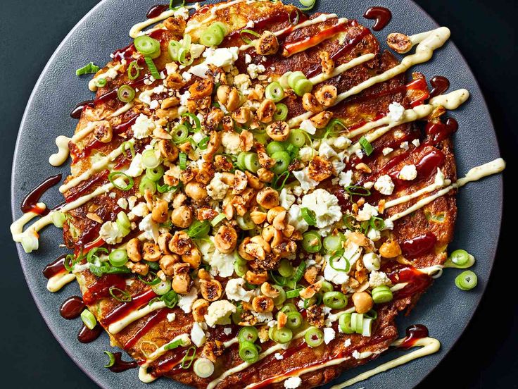 a pizza covered in lots of toppings on top of a blue plate with utensils