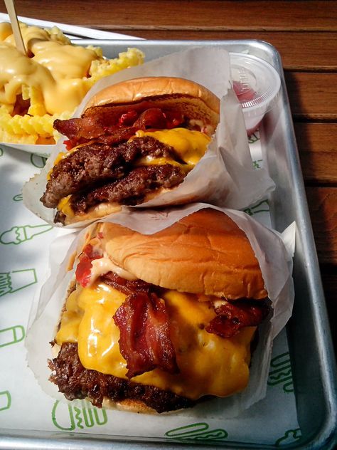 two cheeseburgers with bacon are sitting on a tray