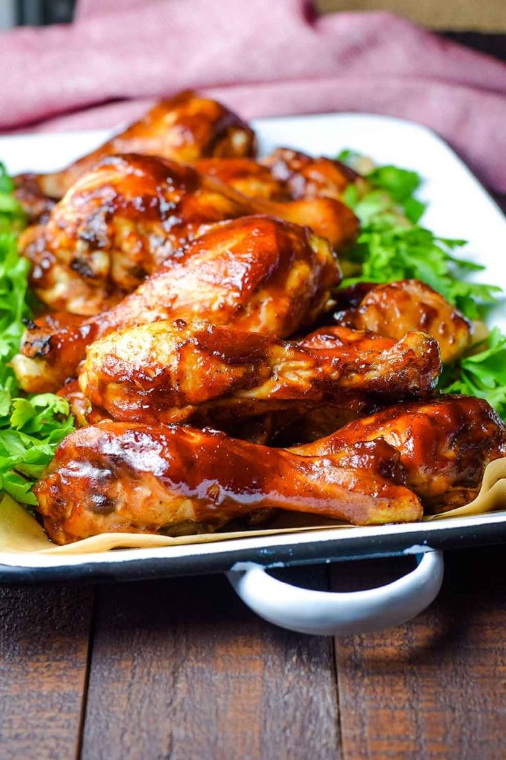 chicken wings with lettuce and sauce on a white plate sitting on a wooden table