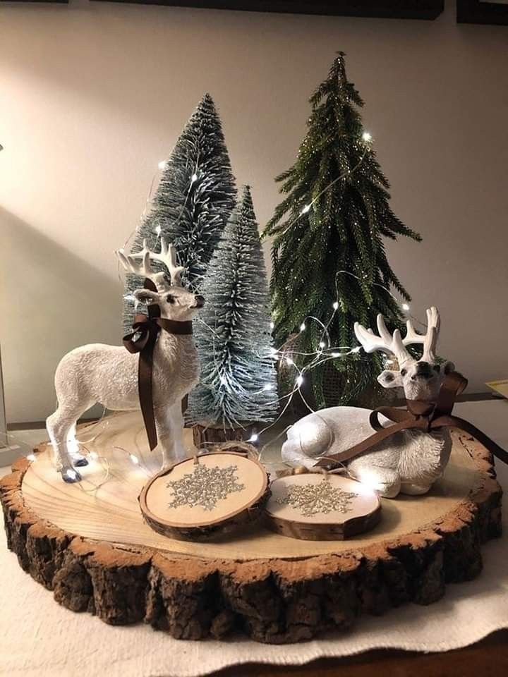 two deer figurines sitting on top of a wooden table next to christmas trees