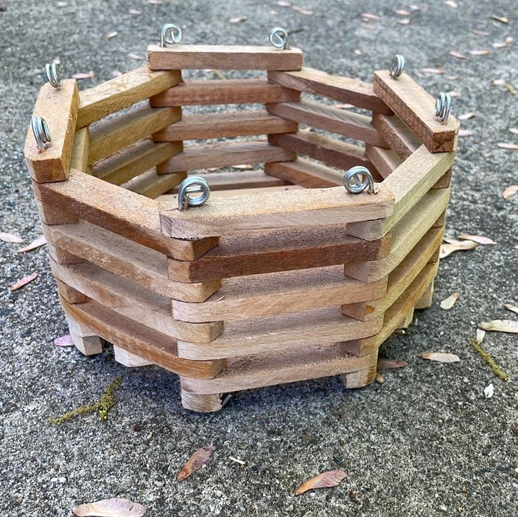 a wooden basket sitting on the ground with nails stuck to it's sides and rivets