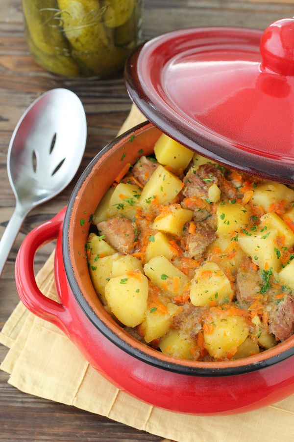 a red casserole dish with meat and potatoes