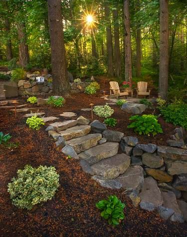 the sun shines brightly through the trees in this backyard garden with stone steps and seating area