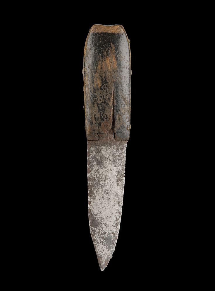 an old metal object with rust on it's side and a knife sticking out of the top