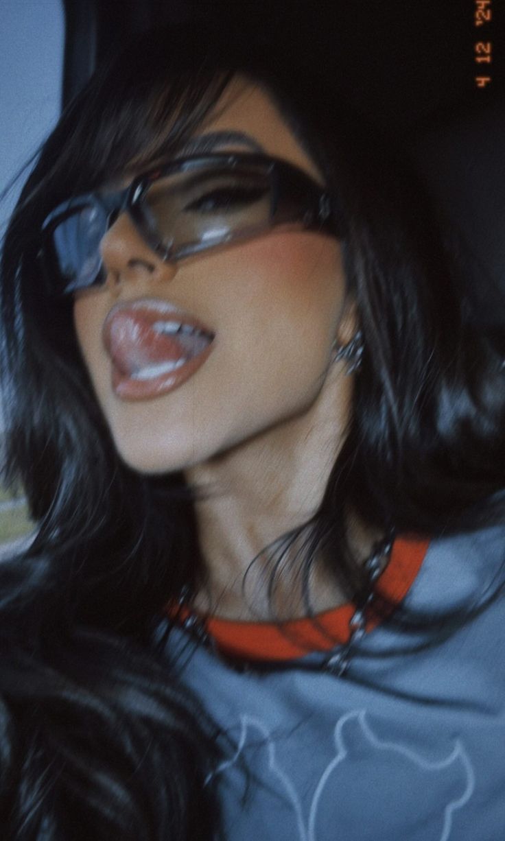 a woman wearing glasses and sticking out her tongue