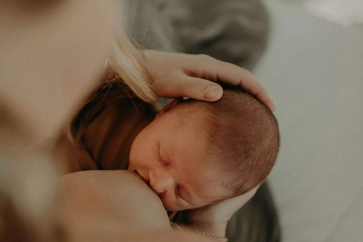 a woman holding a baby in her arms while she is breastfeeding it's head