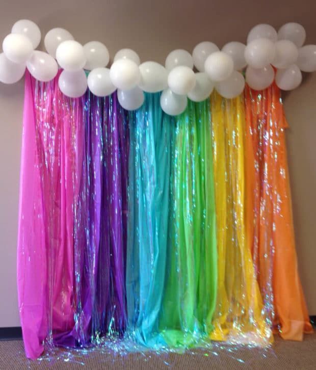 balloons and streamers are hanging from the ceiling in front of a birthday party backdrop