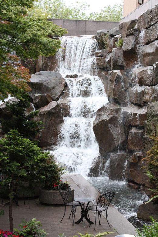 there is a waterfall in the background with tables and chairs