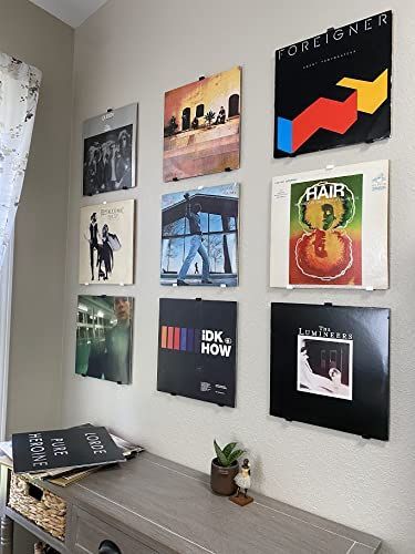 a room with posters on the wall and a dresser in front of it, along with a window