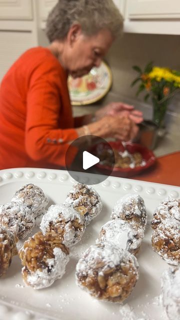 a woman sitting in front of a white plate filled with donuts covered in powdered sugar