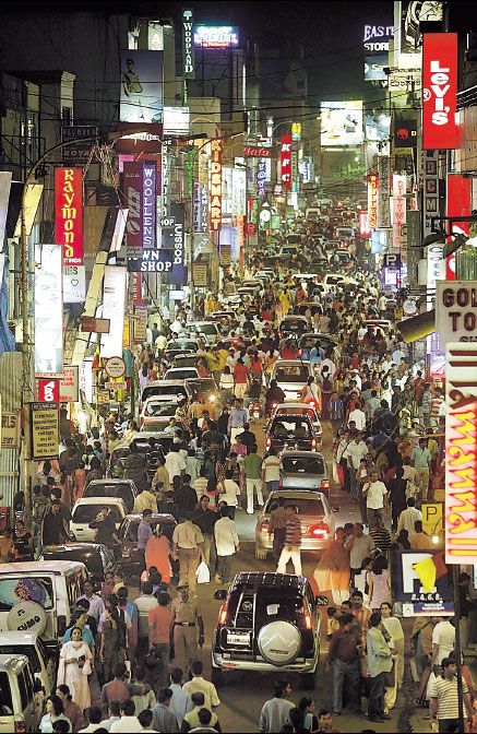 a busy city street filled with lots of cars and people walking around at night time