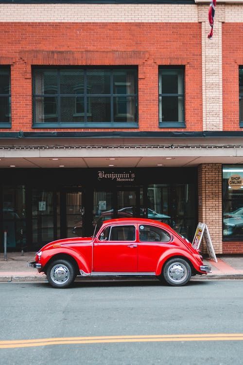 an old red car parked in front of a building