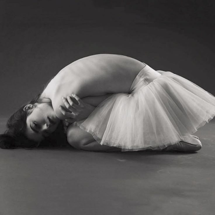 black and white photograph of a woman in a tutu skirt laying on the floor