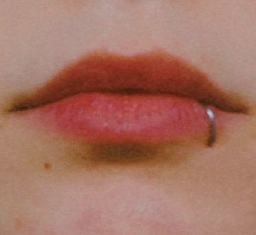 a woman's lip with red lipstick on it, showing the tip of her nose