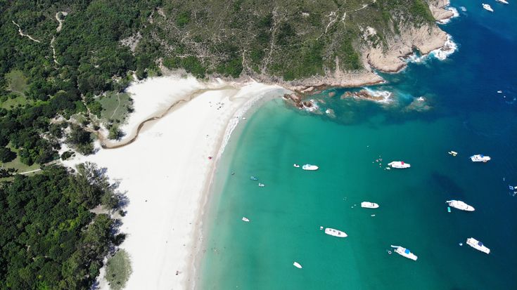 an aerial view of boats in the water near a beach