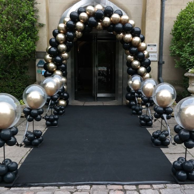 an entrance decorated with black and gold balloons