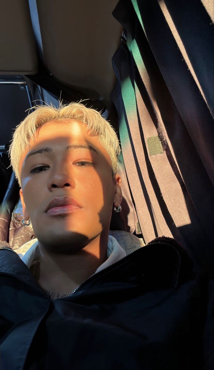 a young man with blonde hair sitting in the back seat of a car and looking off into the distance