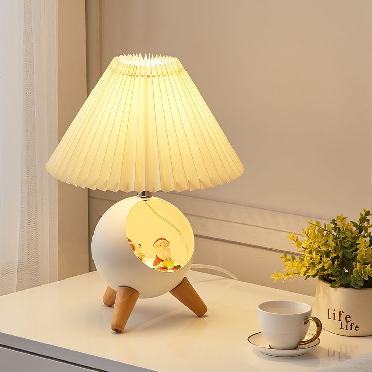 a white lamp sitting on top of a table next to a cup and saucer