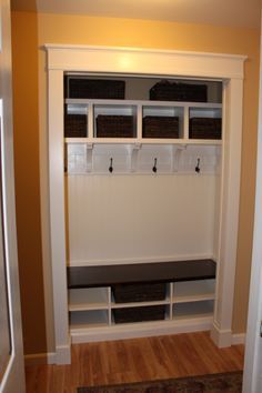 a room with some white shelves and black bins on the wall next to it