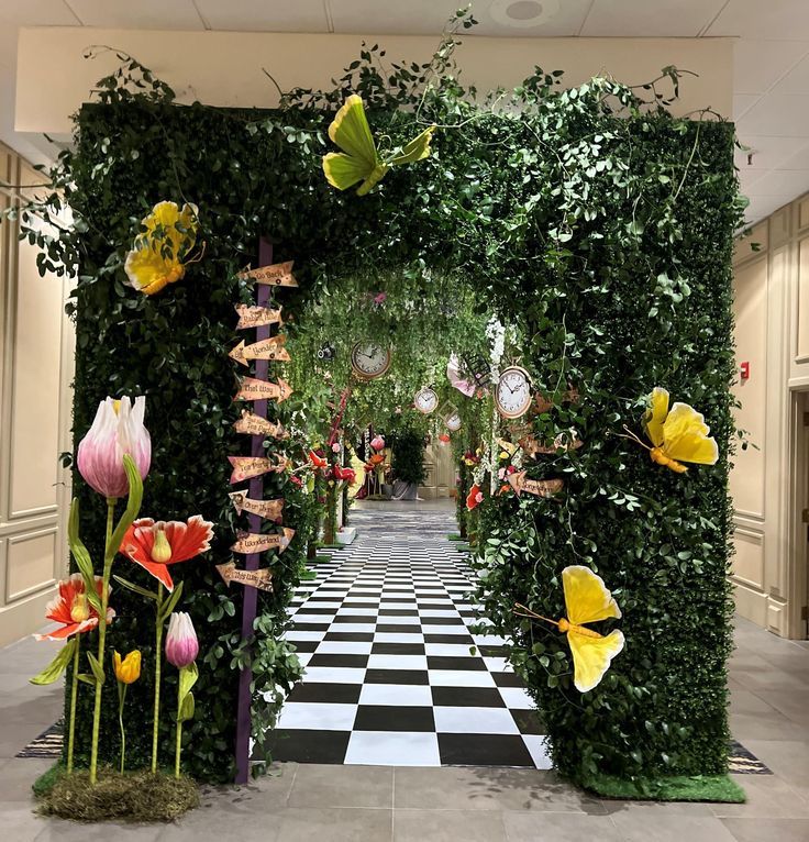 an entrance to a garden with flowers and butterflies on the wall, in front of a checkerboard floor