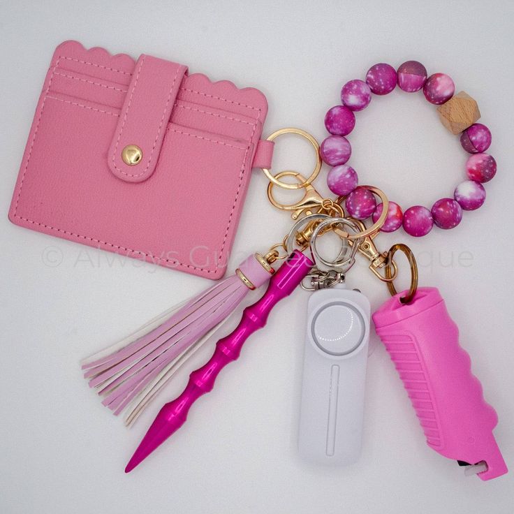 a pink purse, keychain, and other items on a white table top