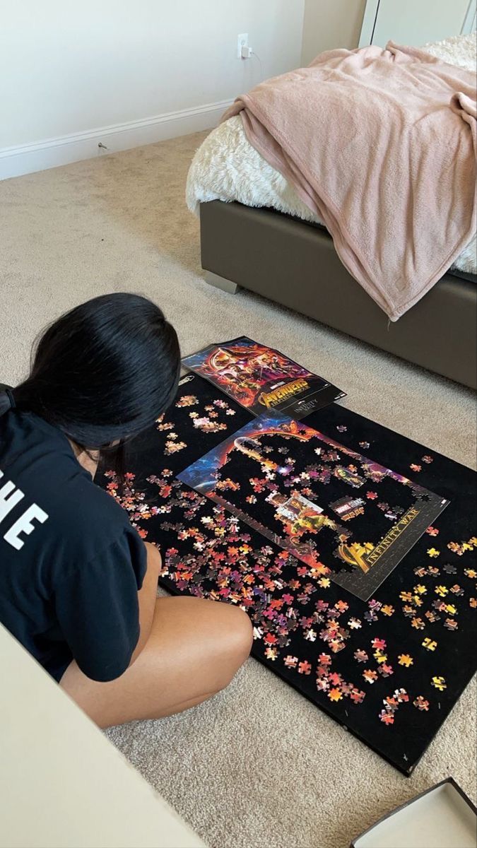 a woman sitting on the floor next to a puzzle