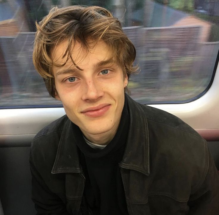 a young man sitting on a train looking at the camera