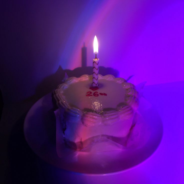 a birthday cake sitting on top of a white plate with a lit candle in the middle