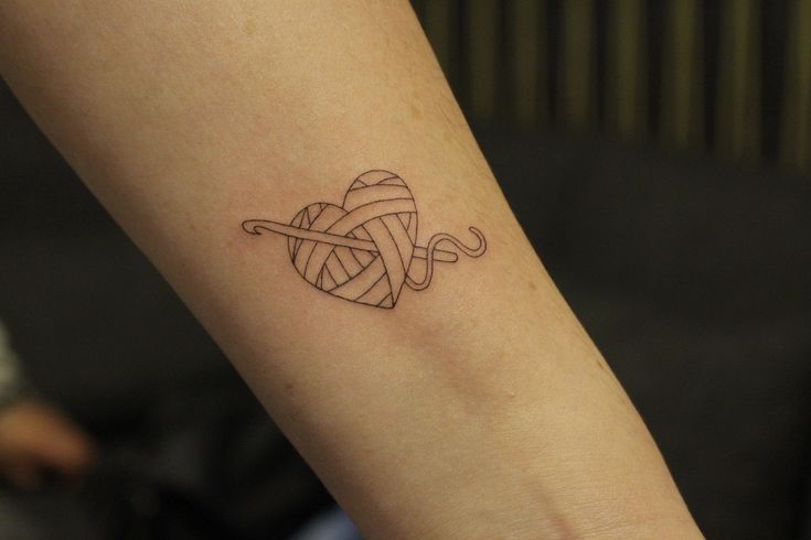 a woman's arm with a tattoo that has a ball of yarn on it