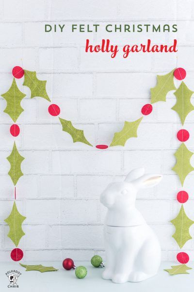 a white bunny sitting next to a christmas decoration with holly garland on it's side