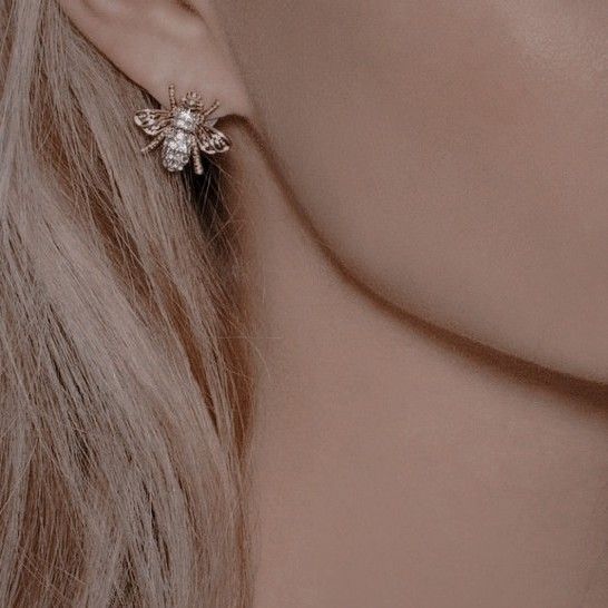 a woman with long blonde hair wearing a pair of earring designs on her ears