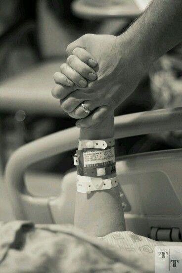 two people holding hands over a hospital bed with an iv tube in the foreground