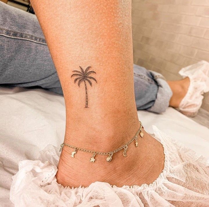 a woman's foot with a small palm tree tattoo on her left side ankle