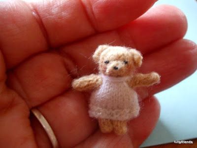 a tiny teddy bear is being held in the palm of someone's left hand