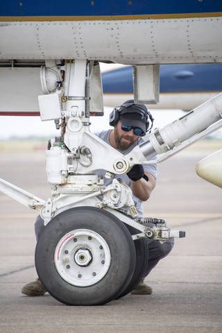 a man is working on an airplane's engine under the wing wheel and landing gear